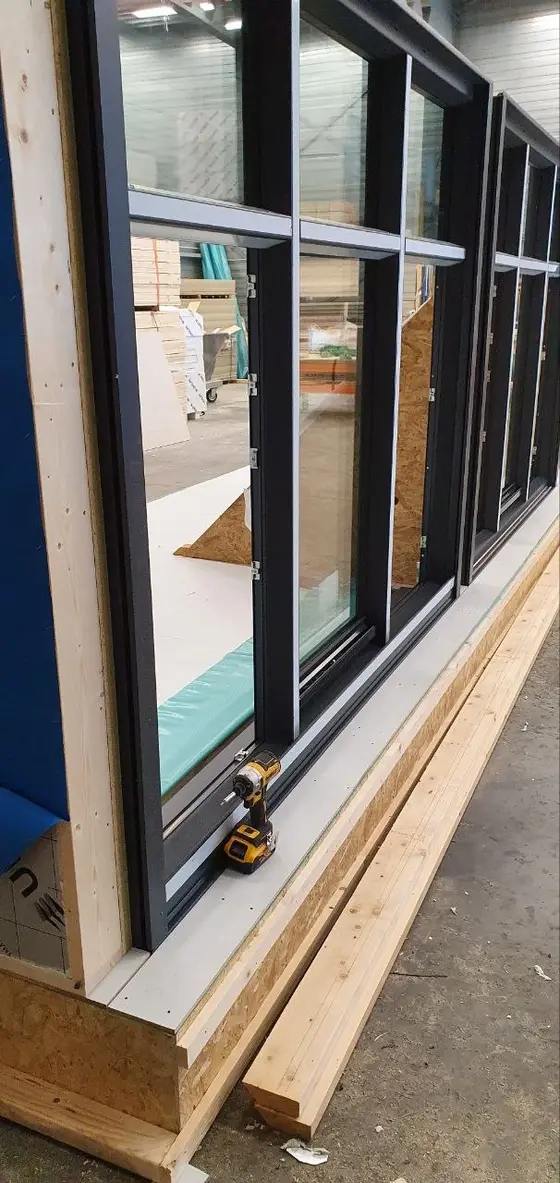 Rij antracieten kozijnen in een houten frame