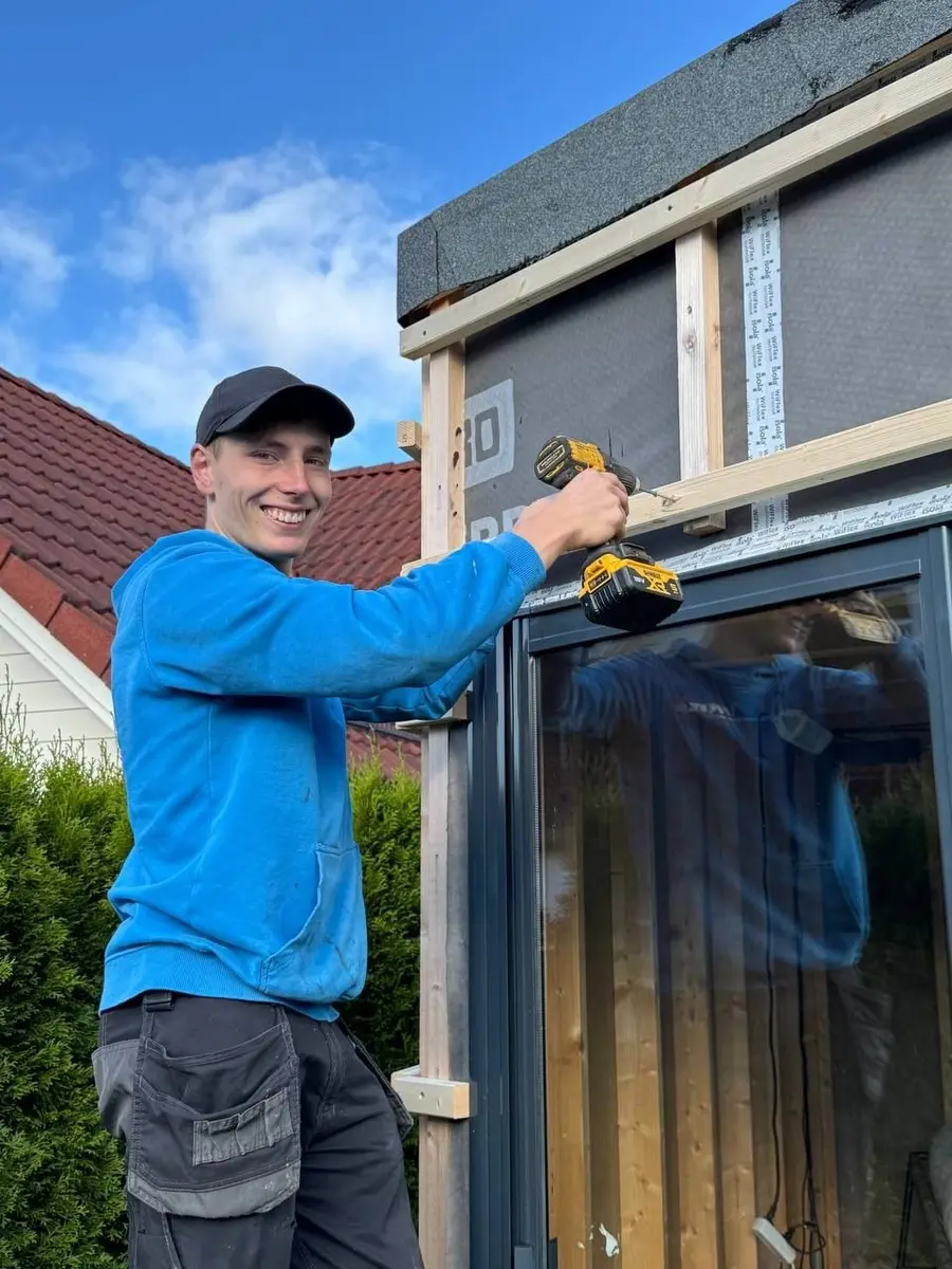 Hidde Schaapman met een accuschroevendrijver aan een houten regelwerk