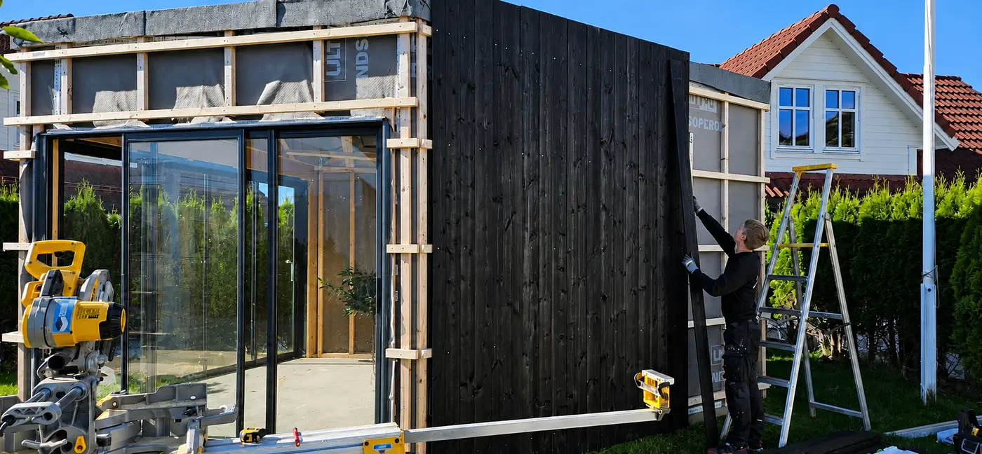 Een tuinhuis wordt betimmerd met zwart geschilderde delen